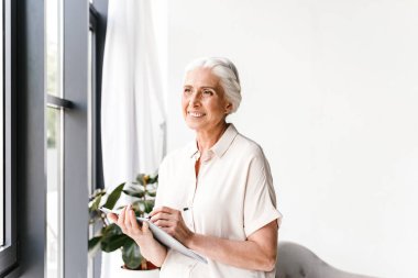 Mutlu olgun iş kadını ofiste dururken not alma