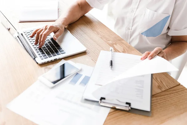 Kapalı dizüstü bilgisayar ile çalışma ofisinde oturan Olgun kadın resim kırpılmış.