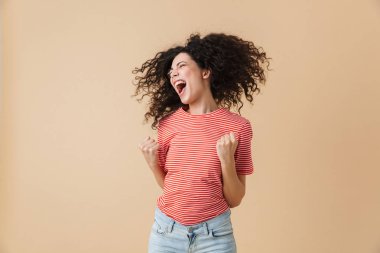 Kazanan jest gösterilen bej duvar arka plan üzerinde izole mutlu genç ve güzel kadın görüntüsünü.