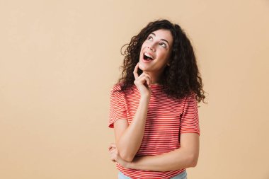 Tatlı rüya genç kadın bir kenara seyir bej duvar arka plan üzerinde izole ayakta görüntüsünü.