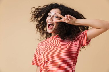 Barış hareketi gösterilen bej duvar arka plan üzerinde izole mutlu genç ve güzel kadın fotoğrafı.