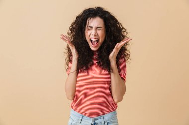 Fotoğrafı agresif çığlık atan genç kadın bej duvar arka plan üzerinde izole sıktı.