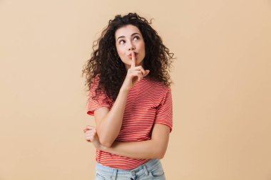 Sessizlik jest gösterilen bej duvar arka plan üzerinde izole sevimli genç kadın fotoğrafı.