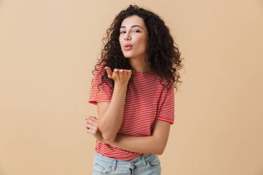 Öpücük bej duvar arka plan üzerinde izole sevimli genç kadın görüntüsünü.