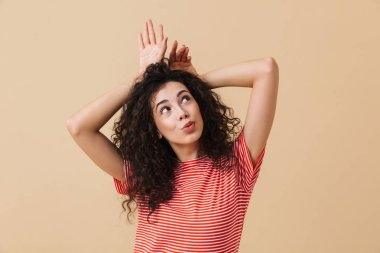 Sevimli genç kadının eğleniyor bej duvar arka plan üzerinde izole görüntü.