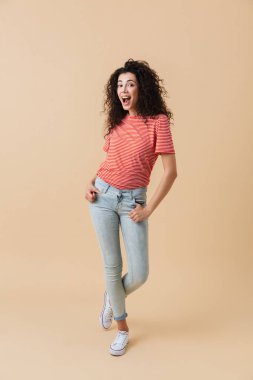 Görüntü izole kamera seyir bej duvar arka plan üzerinde mutlu genç ve güzel kadın.