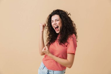 Kazanan jest gösterilen bej duvar arka plan üzerinde izole mutlu genç ve güzel kadın görüntüsünü.