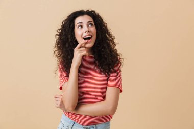 Tatlı rüya genç kadın bir kenara seyir bej duvar arka plan üzerinde izole ayakta görüntüsünü.