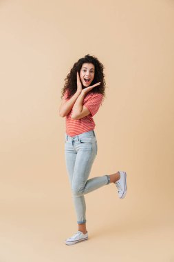 Görüntü izole kamera seyir bej duvar arka plan üzerinde mutlu genç ve güzel kadın.