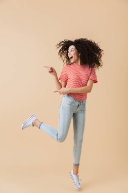 İnanılmaz heyecanlı duygusal genç kadın üzerinde bej duvar arka plan boşaltmak gösterilen izole görüntüsünü.