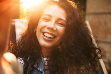 Mutlu genç güzel kıvırcık kadının açık havada Park kameraya bakarak resim.