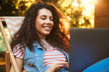 Neşeli duygusal genç güzel kadın resim var bir dinlenme açık havada dizüstü bilgisayar kullanan parkta.