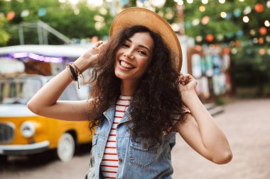 Gülme ve eğlence mekanı veya modern park içinde kalan süre onun hasır şapka dokunmadan kıvırcık kumral mutlu Avrupa kadın 18-20 fotoğrafı