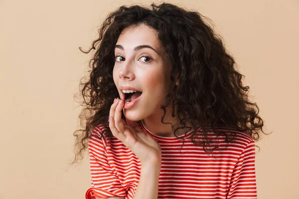 Bej renkli arka plan üzerinde izole duran sevimli güzel genç kıvırcık kadın fotoğrafı. Görünümlü kamera.