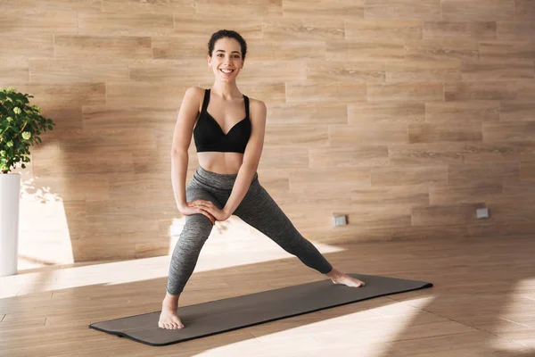 Spor salonunda fitness mat dururken germe egzersizleri yapıyor gülümseyen genç sporcumuz portresi