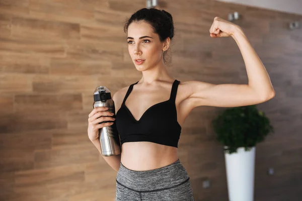 Strong Young Sportswoman Holding Water Bottle While Standing Gym Flexing — Stock Photo, Image