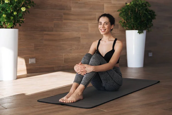 Gülümseyen genç sporcumuz rahatlatıcı jimnastik salonunda fitness mat portresi