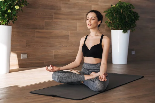 Bir fitness mindere otururken spor salonunda yoga egzersizleri yapıyor sağlıklı bir genç sporcumuz portresi