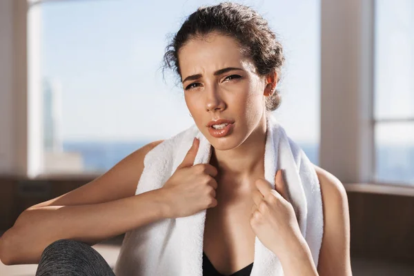 疲惫的年轻 Sportsgirl 坐在她的肩膀上的毛巾在健身房 — 图库照片