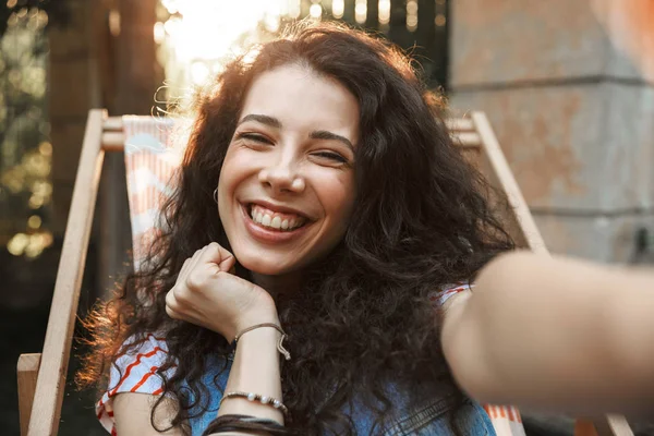 Park lounge sandalyede oturan güneşli günde 18-20 kameraya bakarak ve selfie alarak mutlu neşeli öğrenci kız fotoğraf