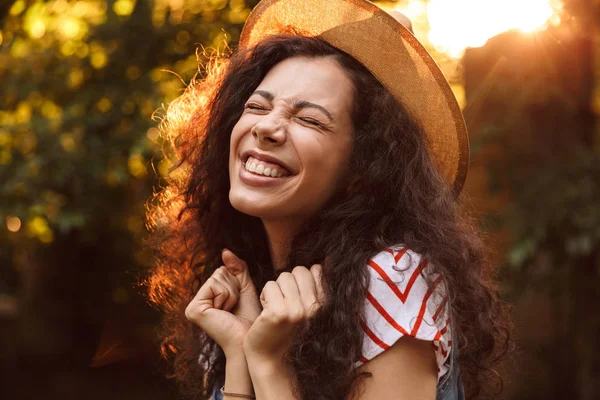 Fotoğraf portre esmer kadın 18-20 hasır şapka yukarıya doğru ağaçlar arka plan ile güneşli gün parkta yürürken arıyorum memnun