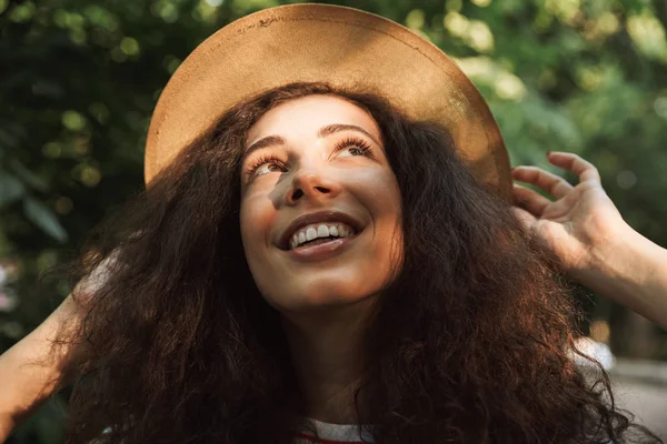 Genç ve güzel kadın 18-20 hasır şapka yukarıya doğru seyir ilgi ile yeşil parkta yürürken giyen kıvırcık kumral portre closeup