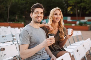 Mutlu güzel genç çift oturma sandalye üzerinde birlikte ve açık havada kahve ile film izlemek