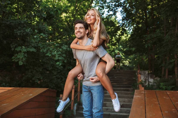 Счастливый Молодой Человек Носит Свою Симпатичную Девушку Спине Городском Парке — стоковое фото
