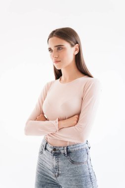 Silah ile ayakta rahat kıyafetler içinde çekici bir genç esmer kız portresi katlanmış ve seyir uzağa beyaz arka plan üzerinde izole