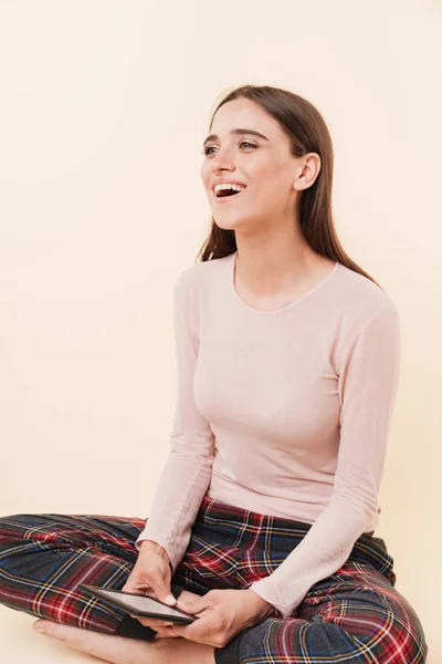 Laughing Young Brunette Girl Dressed Pajamas Holding Ebook While Sit — Stok Foto