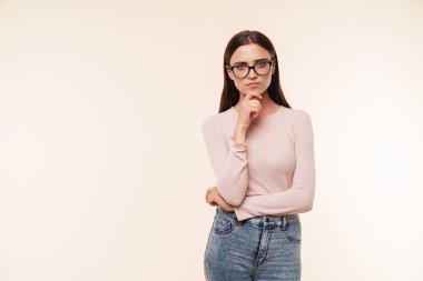Kendine güvenen genç bir esmer kadın pembe arka plan üzerinde izole kamera bakarak gözlük portresi