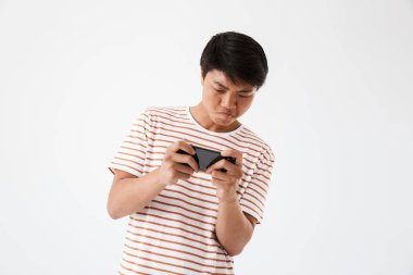 Beyaz bitti izole cep telefonunda oyun odaklı genç bir Asyalı adam portresi