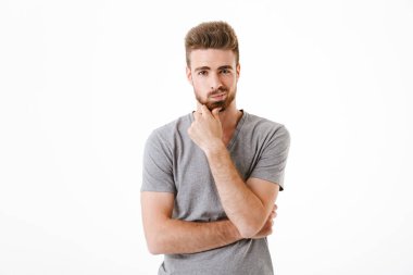 Beyaz duvar arka plan üzerinde izole ayakta düşünceli konsantre yakışıklı genç görüntü.