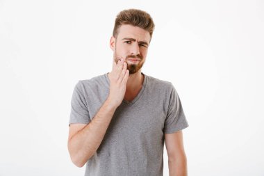 Beyaz duvar arka plan üzerinde izole daimi diş ağrısı ile memnun genç adam görüntüsünü.
