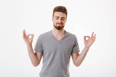 Görüntü konsantre genç adam beyaz duvar arka plan üzerinde izole ayakta meditasyon.