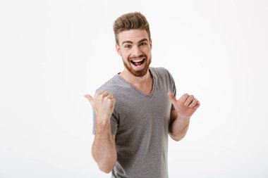 Arka plan beyaz duvar işaret içinde izole ayakta heyecanlı mutlu yakışıklı genç görüntü.