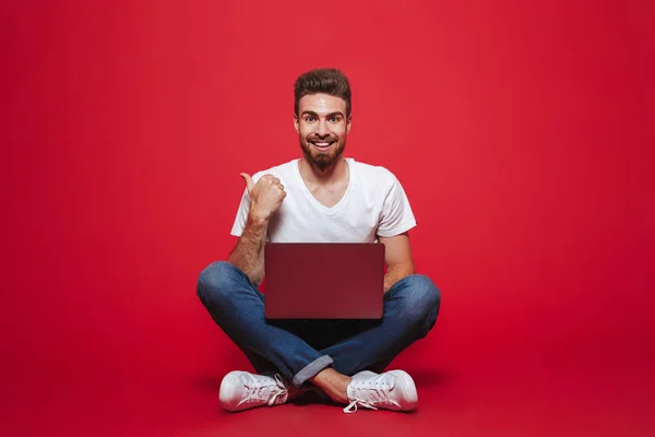 Retrato Joven Barbudo Sonriente Apuntando Espacio Copia Mientras Está Sentado — Foto de Stock