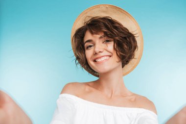 Mavi arka plan üzerinde izole bir selfie alarak genç gülümseyen bir kadın portresi