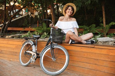 Yaz giysileri Bisiklet ile parkta oturan genç kız gülümseyerek