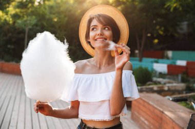 Genç kız parkta pamuk şeker yemek yaz elbise giymiş gülümseyen