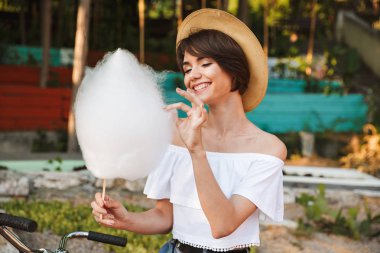 Genç kız parkta pamuk şeker yemek yaz elbise giymiş gülümseyen