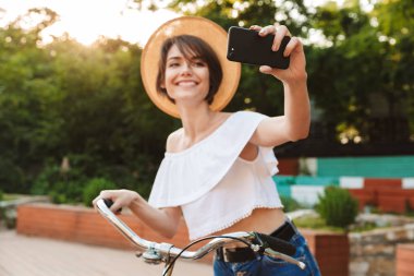 Selfie ile cep telefonu alarak gülümseyen genç kız parkta bisiklet sürme yaz giysileri