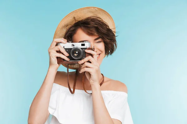 青い背景に分離されたフォト カメラで写真を撮る夏帽子笑顔の若い女性の肖像画 — ストック写真