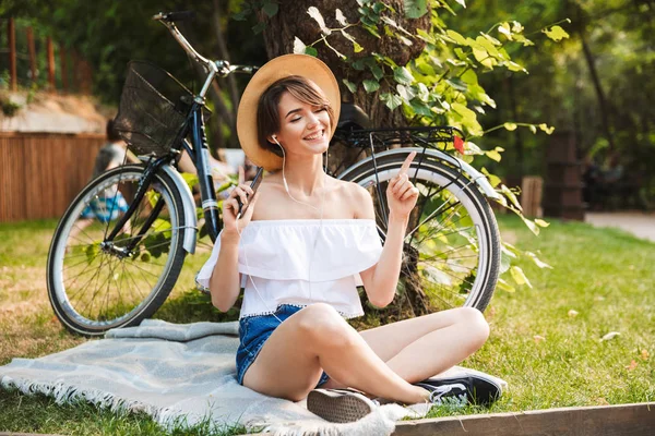 자전거와 공원에 앉아있는 전화와 이어폰으로 음악을 — 스톡 사진