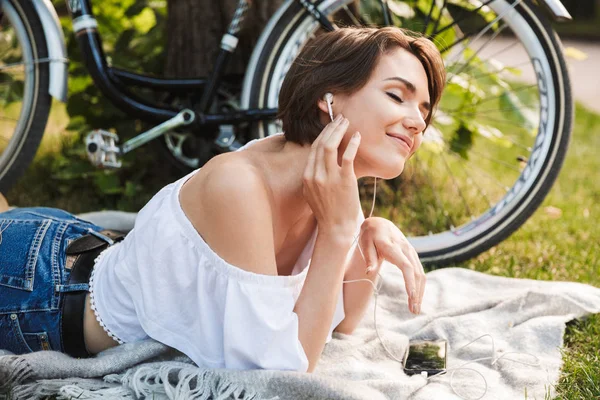 Ragazza Soddisfatta Ascoltando Musica Con Telefono Cellulare Auricolari Mentre Sdraiata — Foto Stock