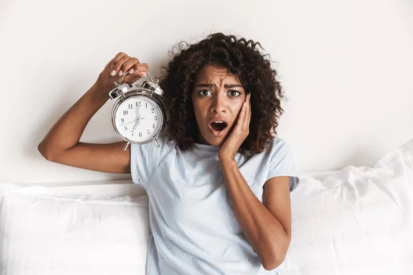 Mujer Africana Joven Confundida Mostrando Despertador Mientras Está Sentada Cama —  Fotos de Stock