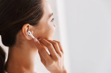 Gülümseyen bir Asyalı kadın kapalı kulaklık ile müzik dinlemek, yakın çekim