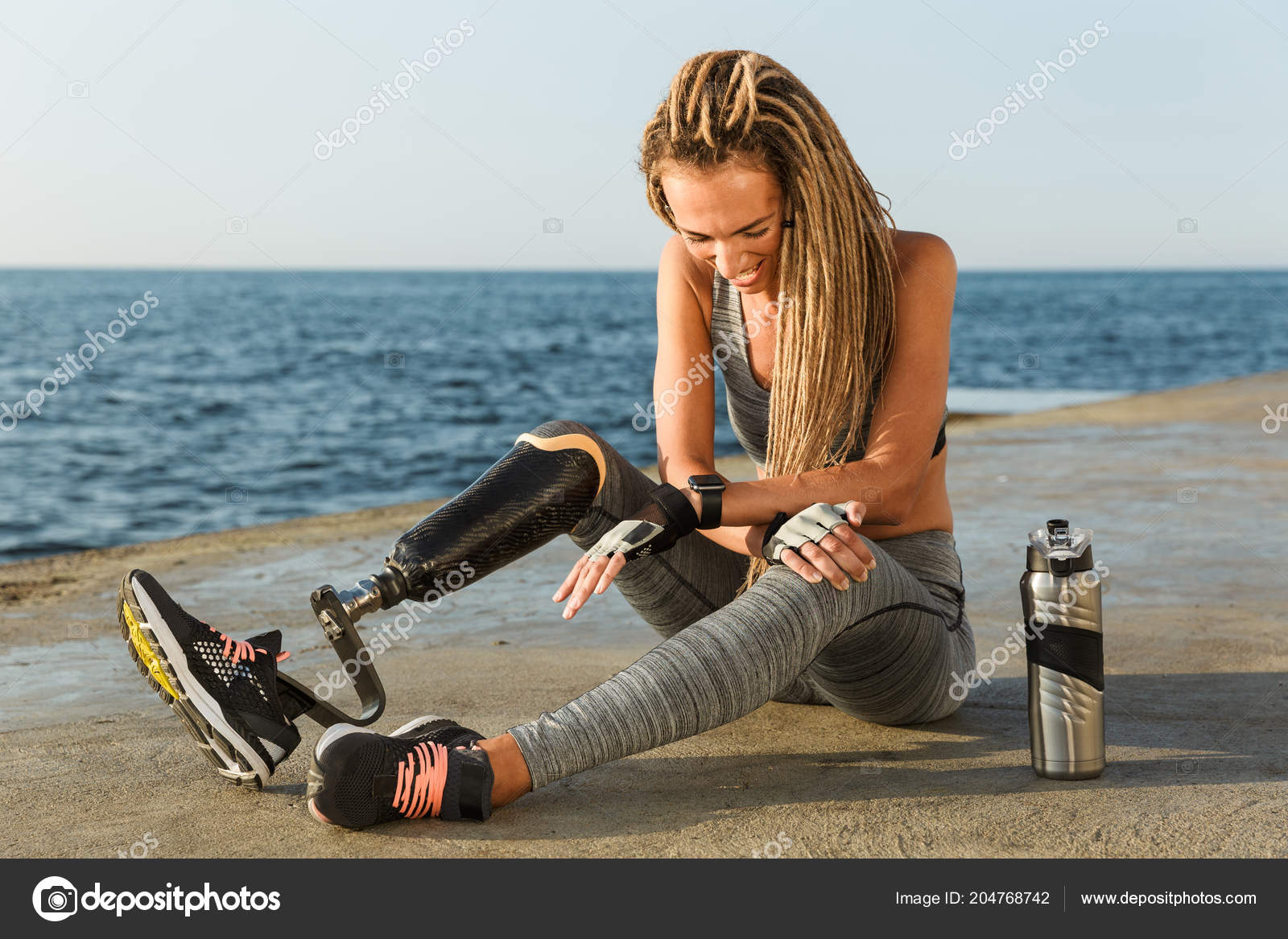Sportswoman with prosthetic leg smiling while using mobile phone