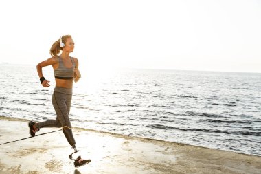 Görüntü şaşırtıcı gençlerin spor kadın plaj açık havada dinleme müzik kulaklık ile çalışan devre dışı.