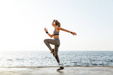 Görüntü şaşırtıcı gençlerin spor kadın plaj açık havada dinleme müzik kulaklık ile çalışan devre dışı.